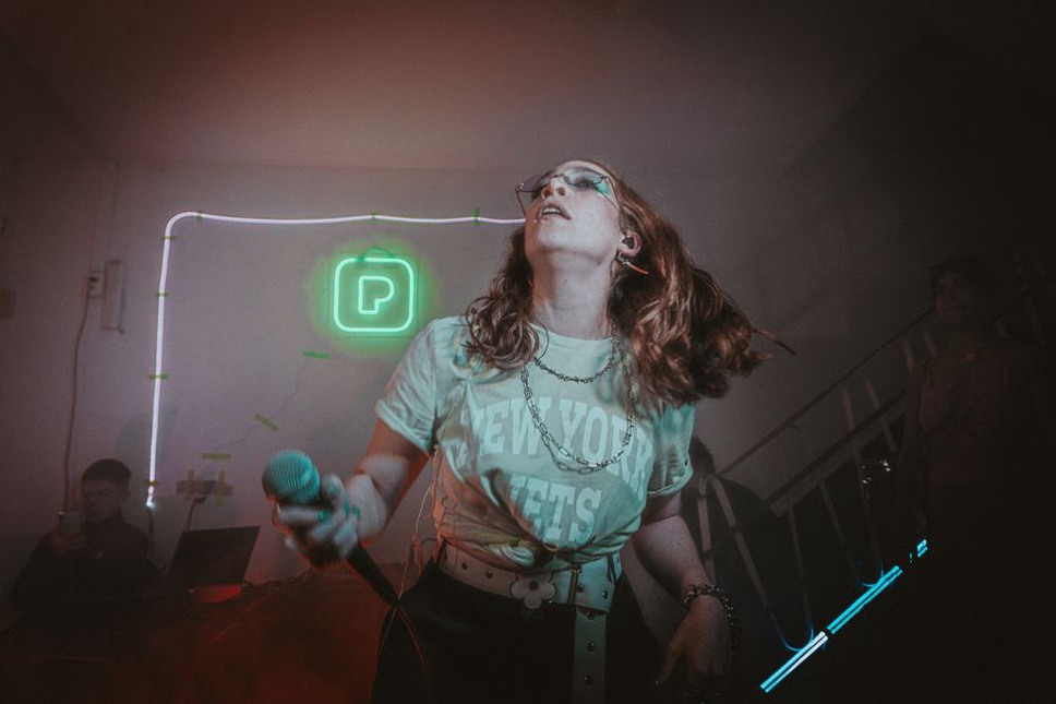 koncert v industriální hale s neonovými světly a kouřem