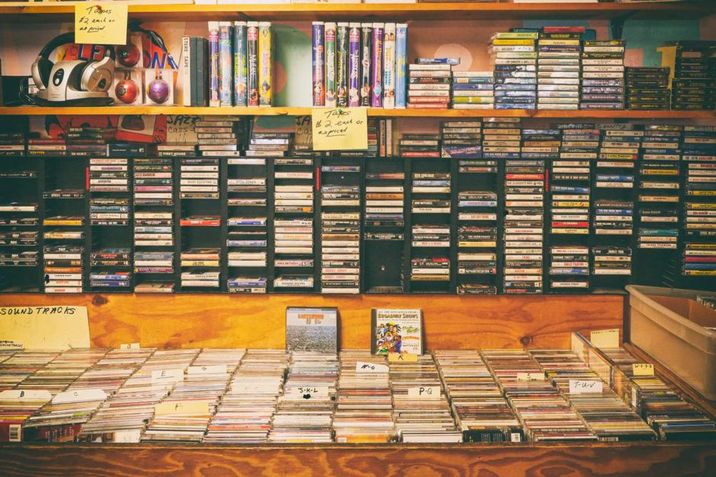 audiokazety a CD-R nosiče s ručně psanými popisky rozložené na dřevěném stole