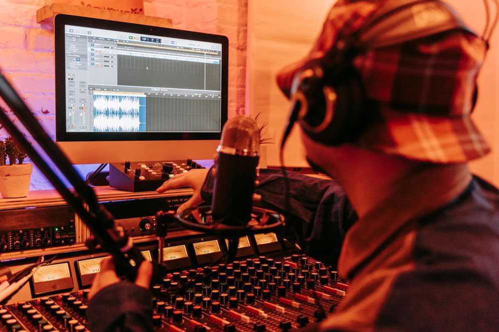 zpěvák ve studiu před monitorem s rozpadající se zvukovou křivkou