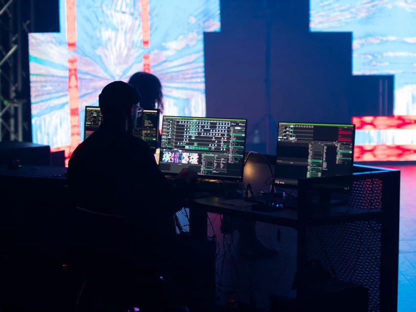 Silueta hudebníka před rozpadlou digitální projekcí