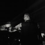 Publikum před temně nasvíceným industriálním pódiem