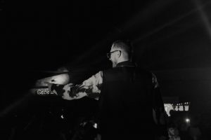 Publikum před temně nasvíceným industriálním pódiem