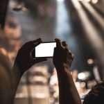 Návštěvník hledá na telefonu informace o koncertě