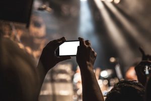 Návštěvník hledá na telefonu informace o koncertě