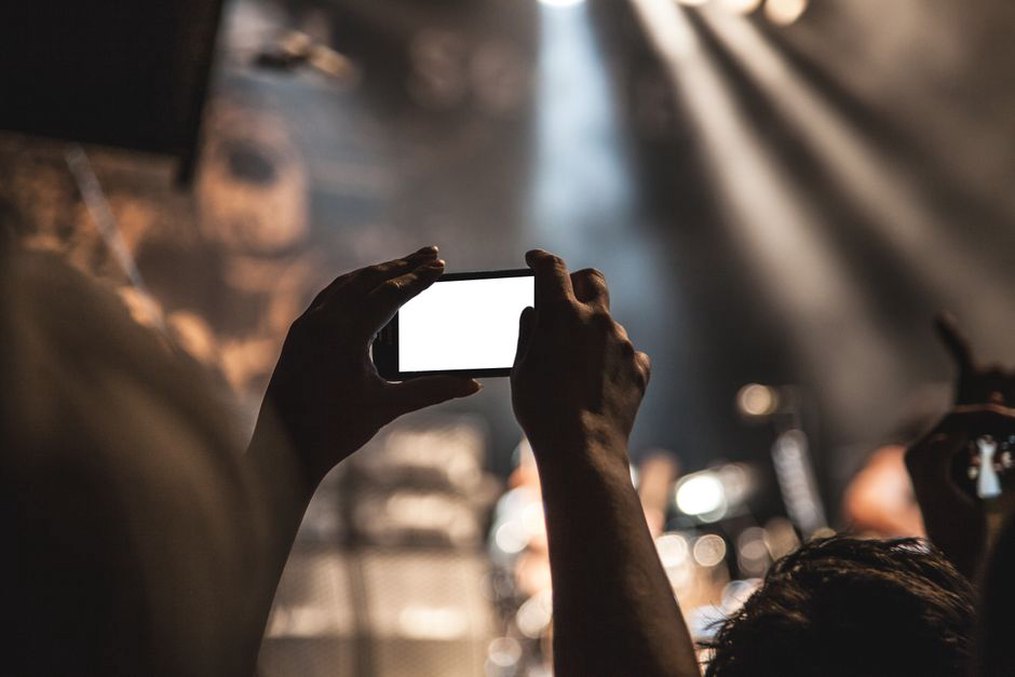 Návštěvník hledá na telefonu informace o koncertě